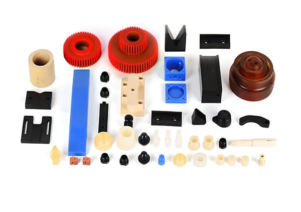 A collection of precision CNC machined plastic parts including red PEEK gears, white PTFE components, and other custom fabricated industrial plastics.
